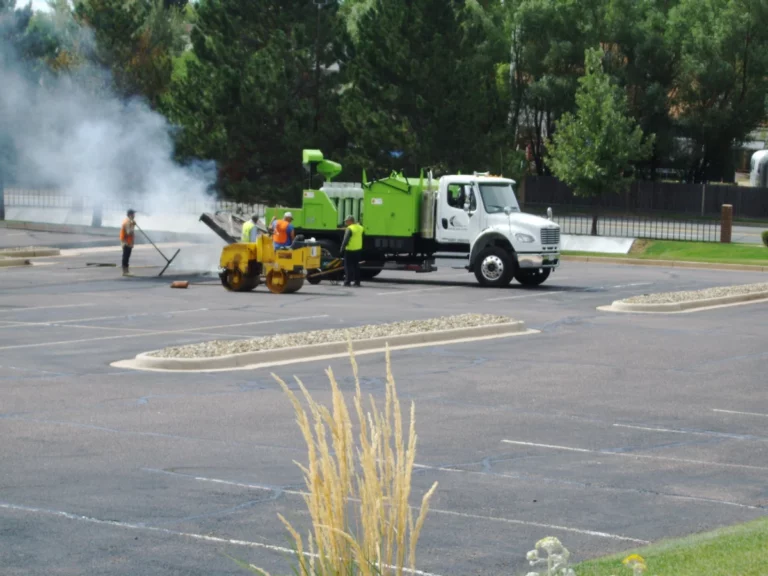 Asphalt Coatings Company crew and roller compacting a parking lot repair in Denver