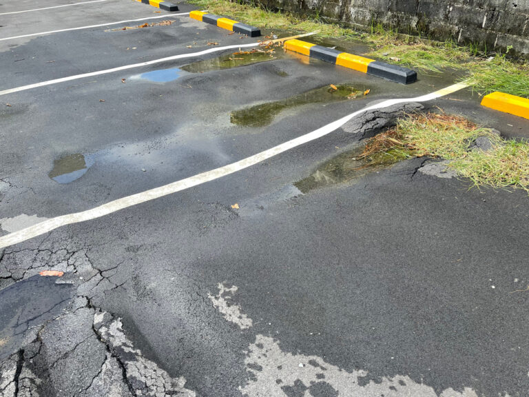 Potholes and alligator cracking in a commercial parking lot drive lane